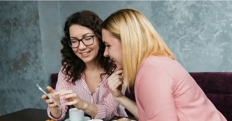 Two women smiling while looking at a smartphone